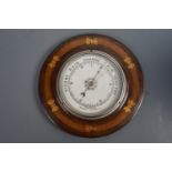A carved and inlaid oak aneroid barometer, circa 1930s, 24 cm