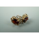 A pair of yellow metal mounted oval garnet stud earrings, the oval fact-cut stones 6 mm x 5 mm