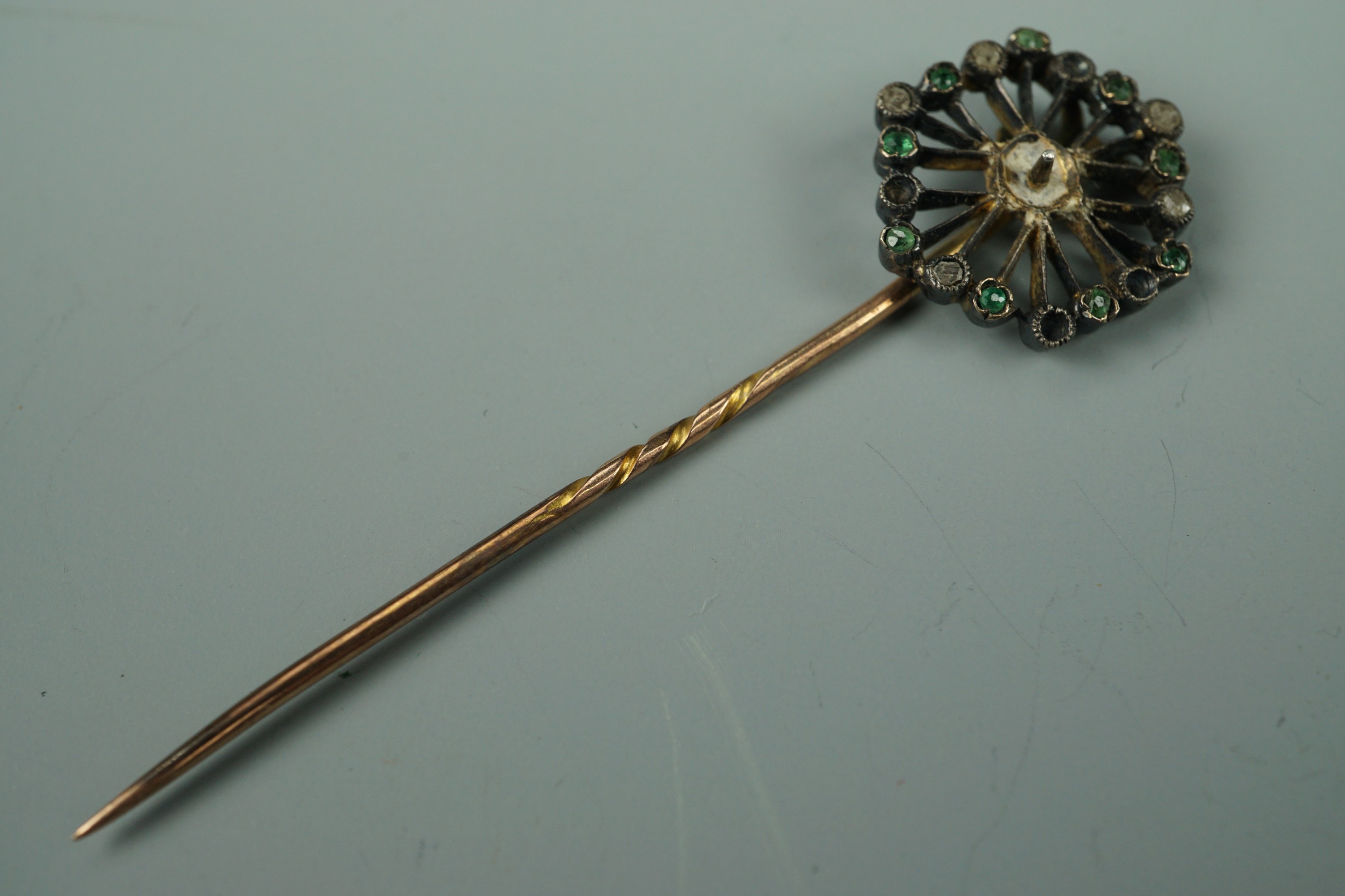 An antique yellow-metal stick pin, set with green and white stones, tested as gold, 3.2g (a/f)
