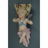 A late 19th Century Austrian porcelain wall pocket modelled as a cherub in flight, carrying a basket