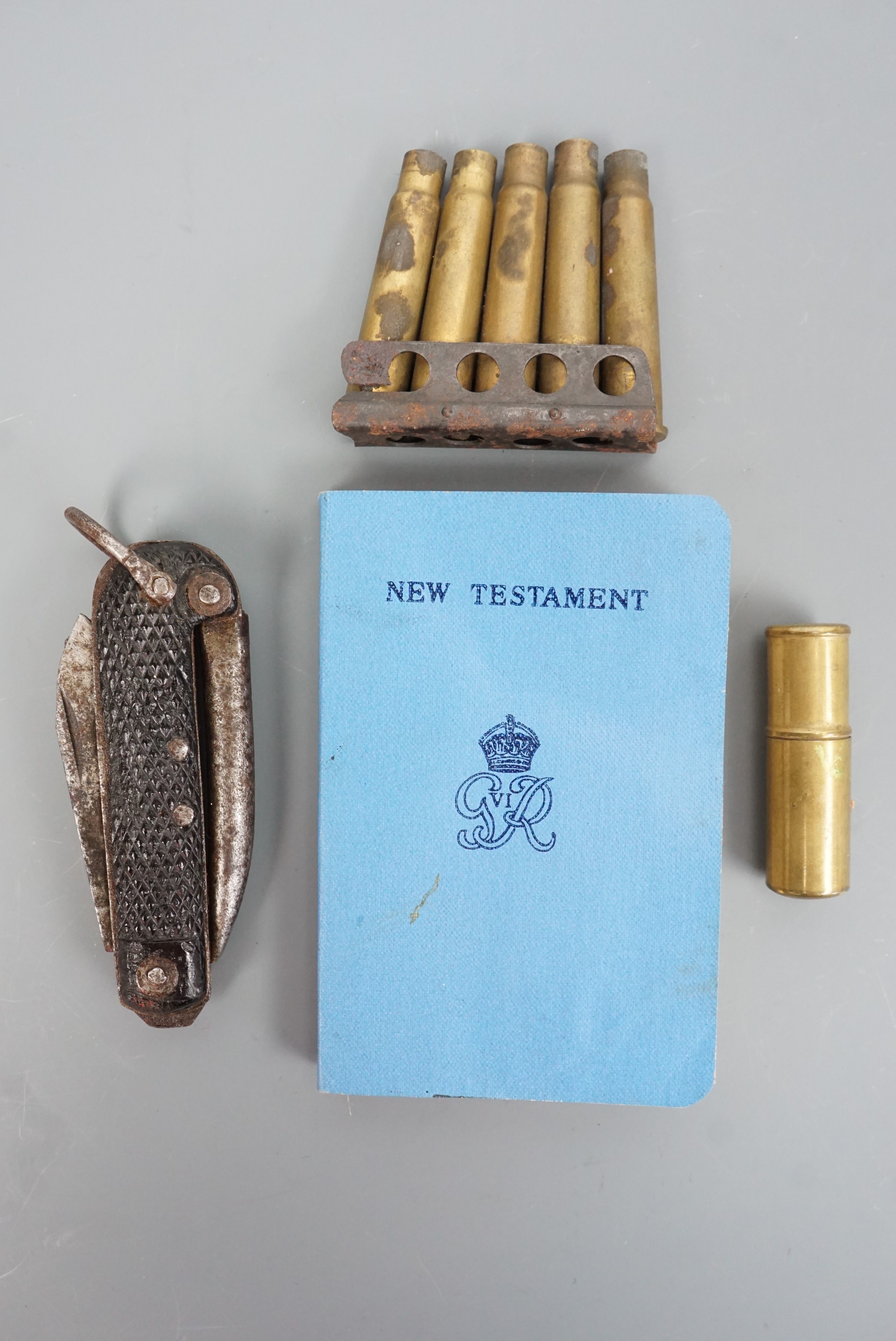 A Second World War Utility lighter, a 1944 soldier's New Testament, a jack knife and clip of