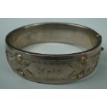 A late 19th / early 20th Century white metal hinged bangle, engraved, faced with yellow metal