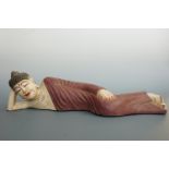 A carved and painted reclining Buddha, 60 cm long