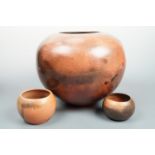 A large contemporary studio pottery compressed-oviform smoky glazed terracotta vase and two
