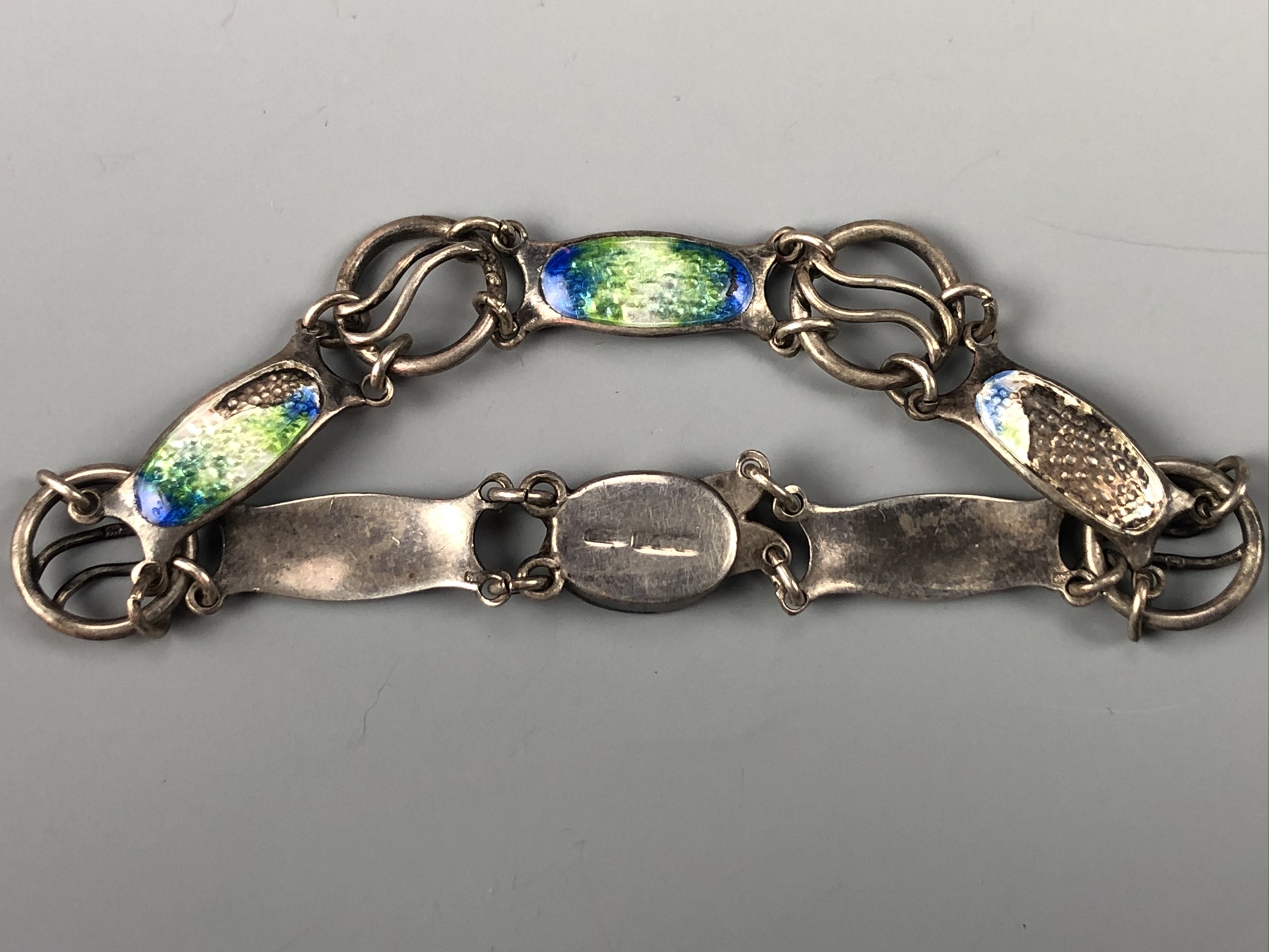 An antique Arts and Crafts influenced basse-taille enamelled silver bracelet, having organic plaques