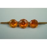 A late 19th / early 20th Century yellow metal bar brooch set with facet-cut amber, 7.5 cm, 7 g