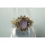 A contemporary diamond and amethyst dress ring, having a central oval cut amethyst of .9ct, framed