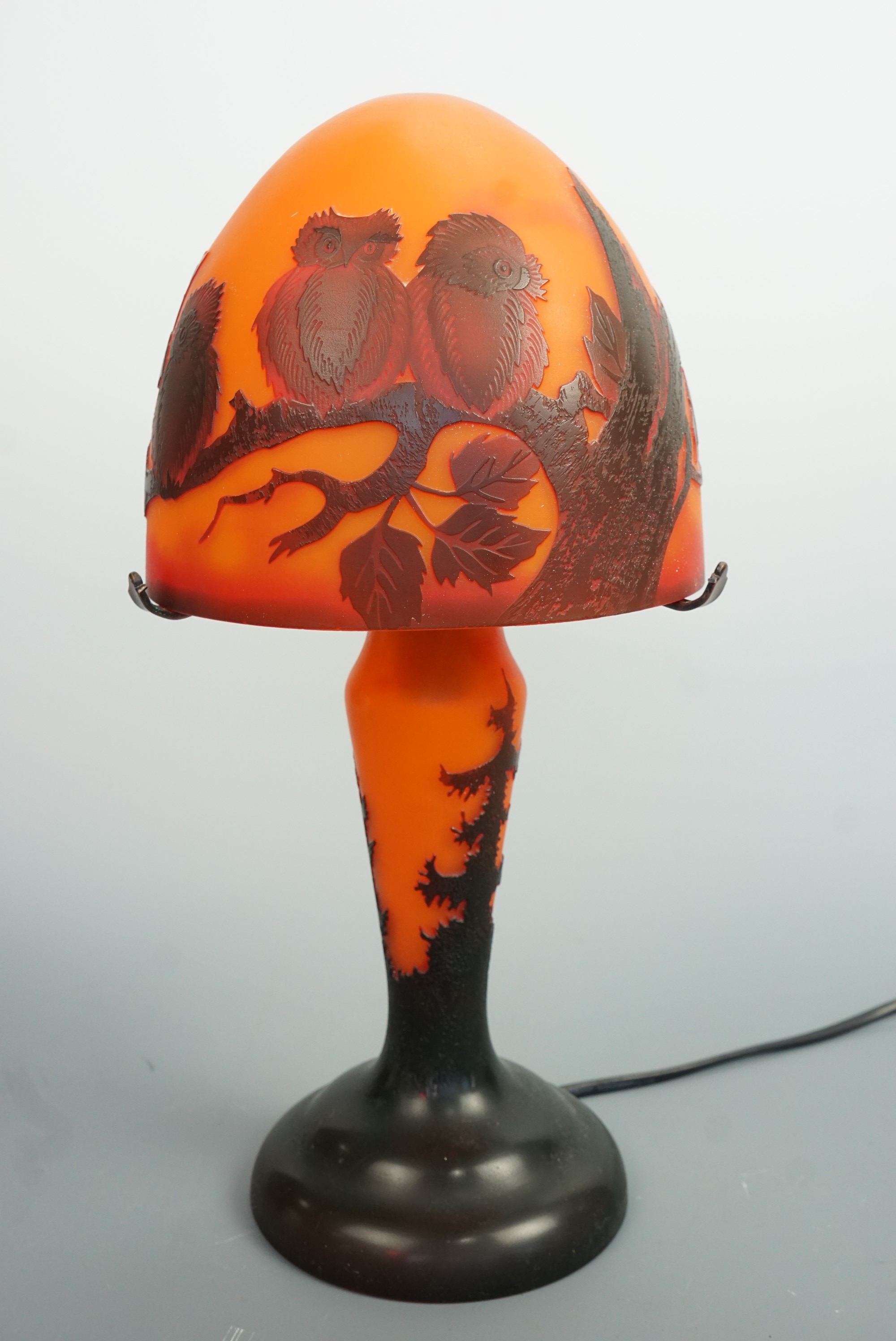 A reproduction Galle glass table lamp, of organic form, the shade decorated with owls perched on a
