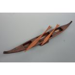 An ethnic carved hardwood boat and oars, 45 cm