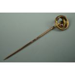 A late 19th / early 20th Century yellow metal stick pin with coiled terminal set with a pink