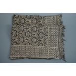 A vintage woven throw decorated in an arabesque pattern in silver coloured thread on a black ground
