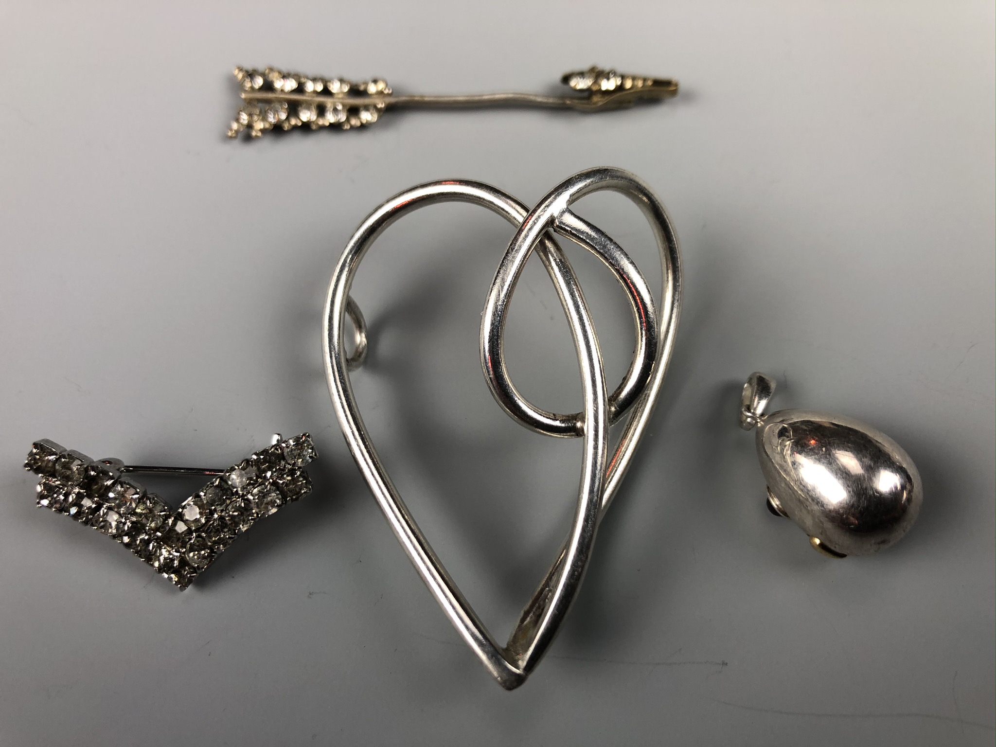 A contemporary white metal oviform pendant, a vintage diamante jabot pin, a double chevron brooch
