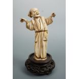 A Meiji Japanese okimono depicting a performer, affixed to a carved wooden base, 16 cm