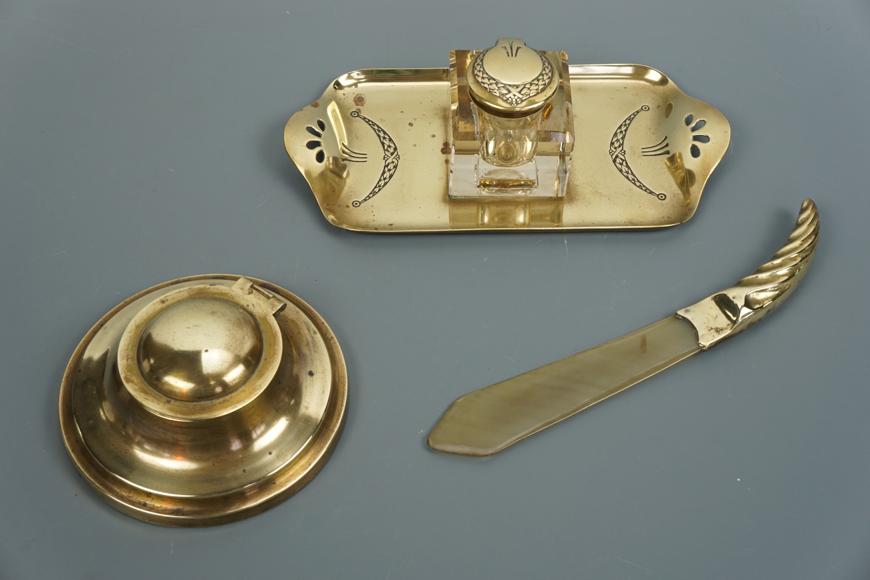 Two early 20th Century brass ink wells and a brass-mounted horn paper knife