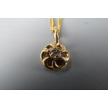 A small 9 ct gold flowerhead pendant on a fine link yellow metal neck chain, 2.0 g