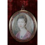 A George III pendant portrait miniature, of a woman with bouffant hair wearing a pink dress and