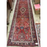 Modern Saruq runner with a medallion and all-over stylised floral design on a red ground with