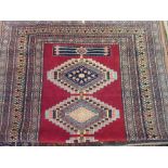 Pakistan rug of Caucasian design with geometric medallions on a wine red ground with borders