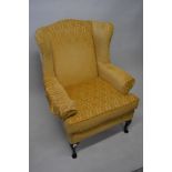 Modern gold figured damask upholstered wing armchair on cabriole supports with pad feet