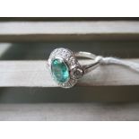 18ct White gold oval emerald and diamond cluster ring, the emerald approximately 0.75ct, the