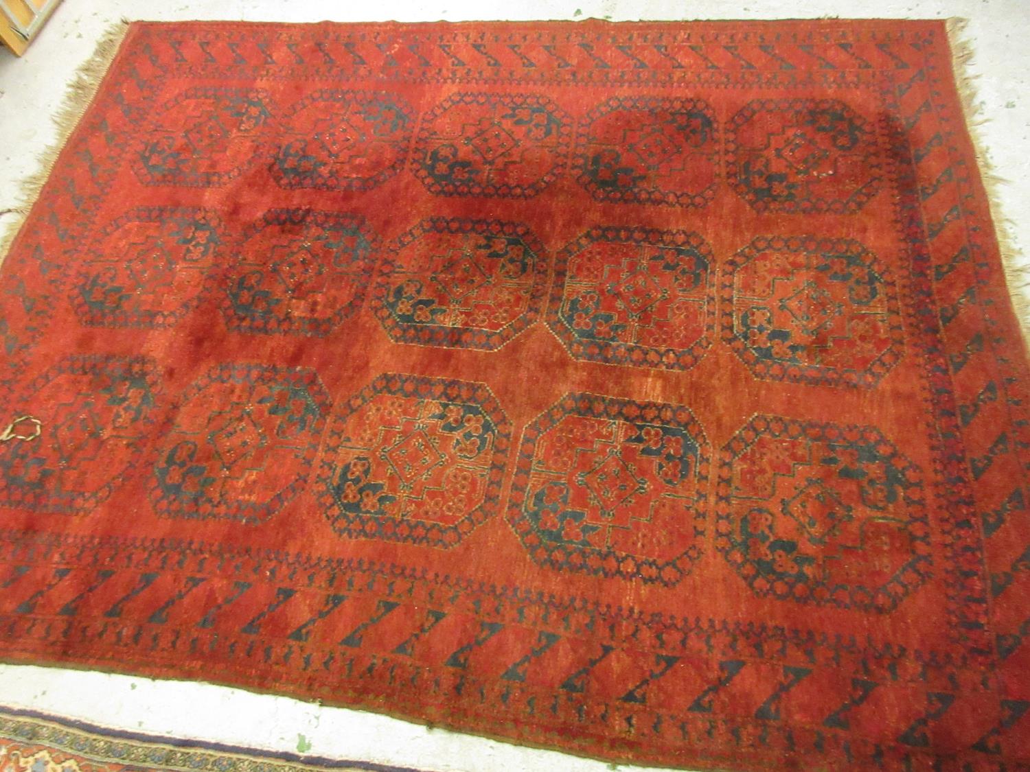 Afghan carpet with typical gol design on a red ground, 10ft x 7ft 6ins approximately Would benefit