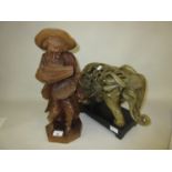 Carved wooden figure of a seated man, together with a ceramic figure of an elephant