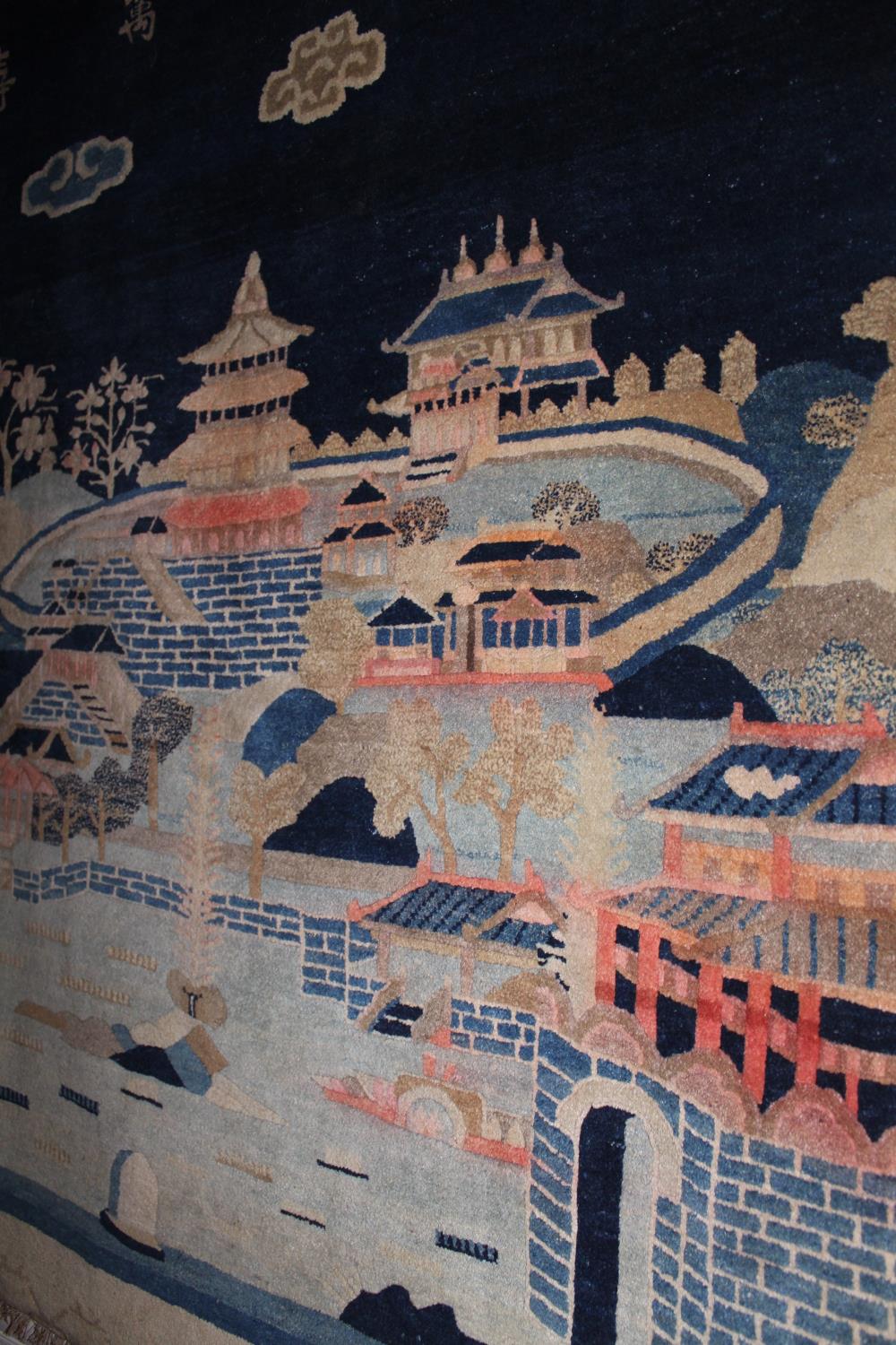 Chinese rug woven with a landscape design in shades of blue, pink and beige beneath a row of seven