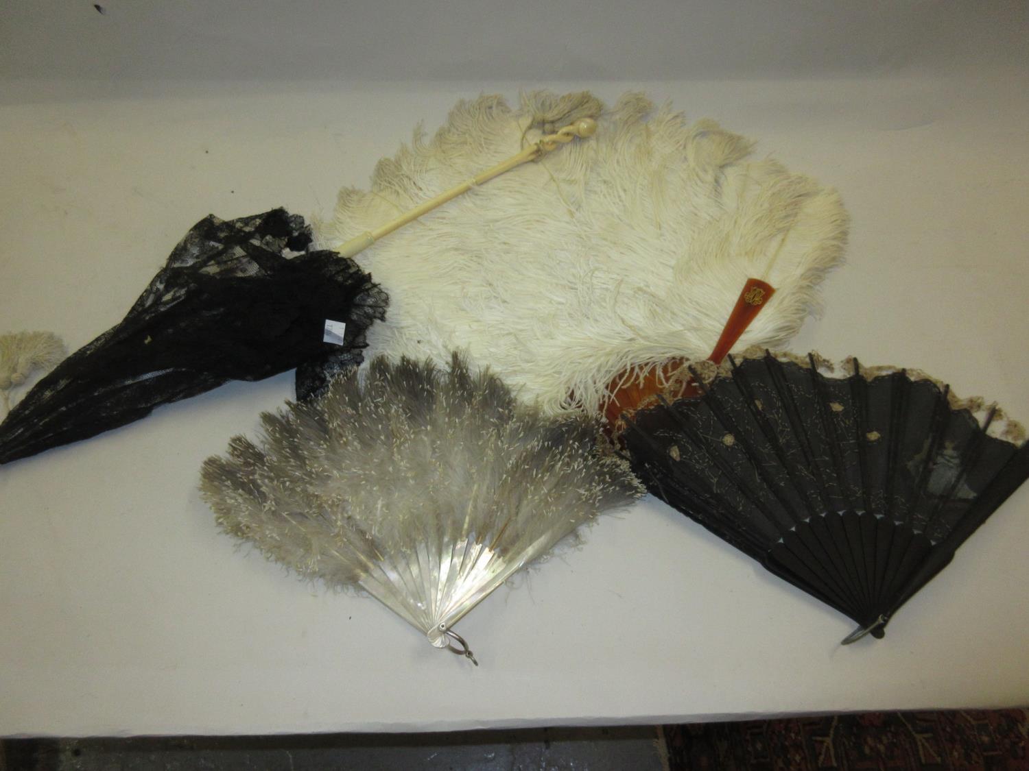 Ostrich feather fan, mother of pearl and feather fan, a black lace fan, together with an ivory and