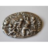 Oval white metal brooch decorated in relief with cherub artists, 2ins wide