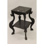 Late 19th Century carved and ebonised two tier vase stand / occasional table on winged gryphon