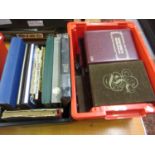 Red and black box containing a quantity of various stamps in albums, match box covers, First Day