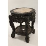 Chinese circular carved hardwood vase stand, the shaped rouge marble inset top above a heavily