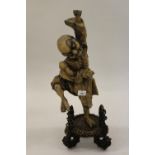 Chinese root carving in the form of a dancing figure with glass eyes on an associated tripod base,