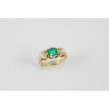 AN EMERALD AND DIAMOND THREE STONE RING the emerald-cut emerald is set with two cushion-shaped old
