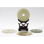 FOUR CHINESE CELADON JADE BI DISCS, with archaistic style stylised ruyi and floral decoration,