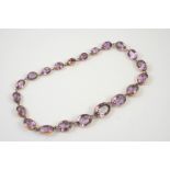 A VICTORIAN AMETHYST RIVIERE NECKLACE formed with graduated oval shaped amethysts in rose gold