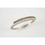 A FANCY COLOURED DIAMOND AND DIAMOND CROSS-OVER HINGED BANGLE set to one side with circular fancy