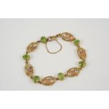 A PERIDOT AND GOLD BRACELET formed alternately with oval-shaped peridots and foliate two colour gold