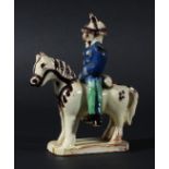 SLIPWARE GROUP OF A HORSE AND RIDER, in cream, brown, blue and green on a terracotta body, height