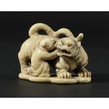 JAPANESE IVORY NETSUKE OF A MAN CROUCHING BY A TIGER, Meiji, signature and seal to base, length 5cm