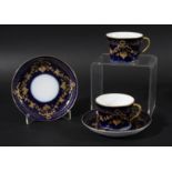 PAIR OF RUSSIAN PORCELAIN CUPS AND SAUCERS, Gardner Factory, with gilt floral swags on a dark blue