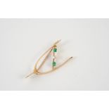 A GOLD, EMERALD AND DIAMOND WISHBONE BROOCH the 15ct gold wishbone is mounted with two rectangular-