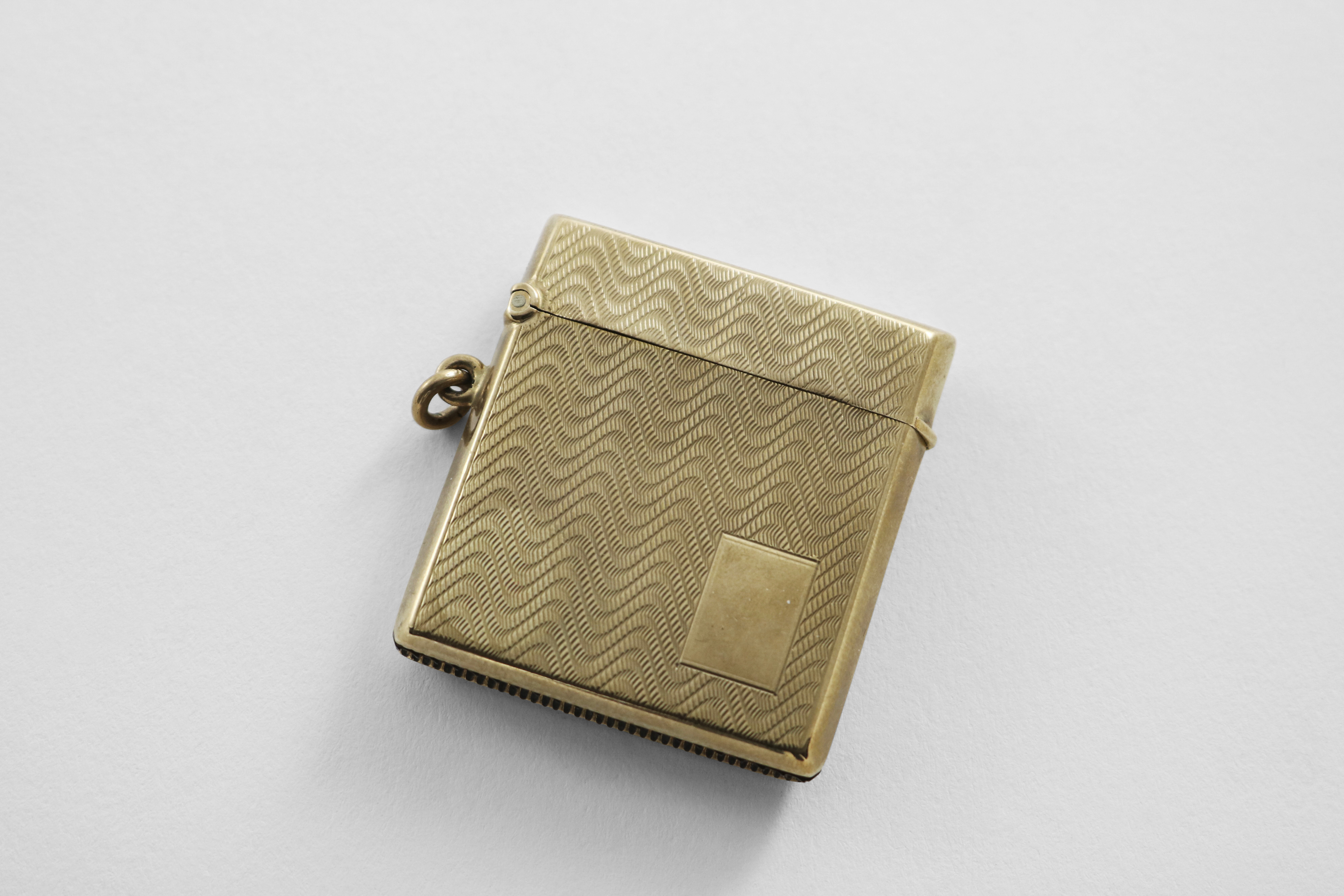 AN EARLY 20TH CENTURY 9 CT. GOLD VESTA CASE with wavy engine-turning and a vacant rectangular