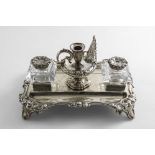 A VICTORIAN SILVER INKSTAND of shaped rectangular outline with a floral scroll border, two mounted