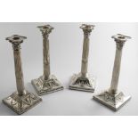 A PAIR OF GEORGE III CORINTHIAN COLUMN CANDLESTICKS on bevelled square bases with embossed urns &
