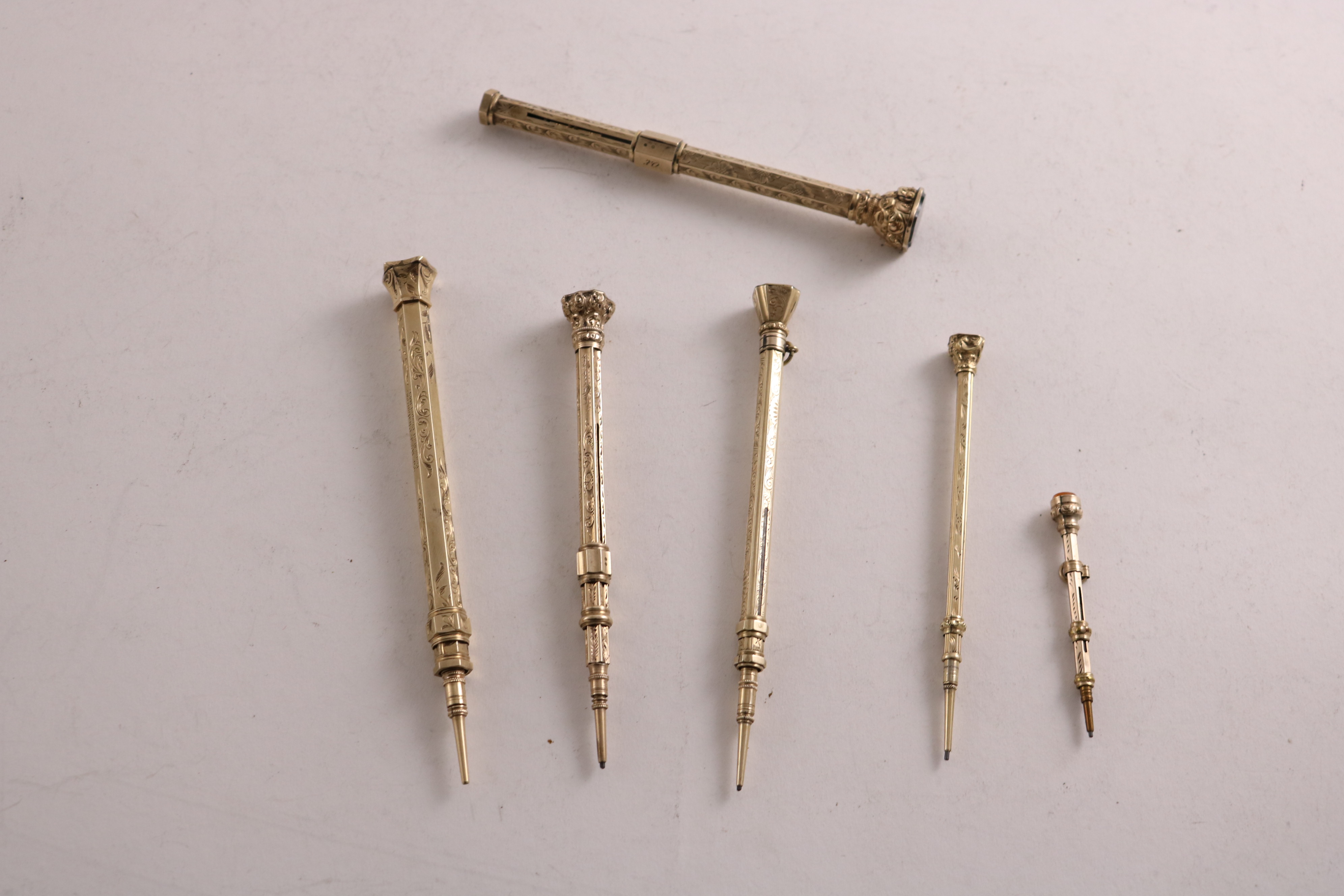 SIX VARIOUS LATE VICTORIAN GOLD-CASED, COLUMN-TYPE PENCILS (one with an inscription); the longest