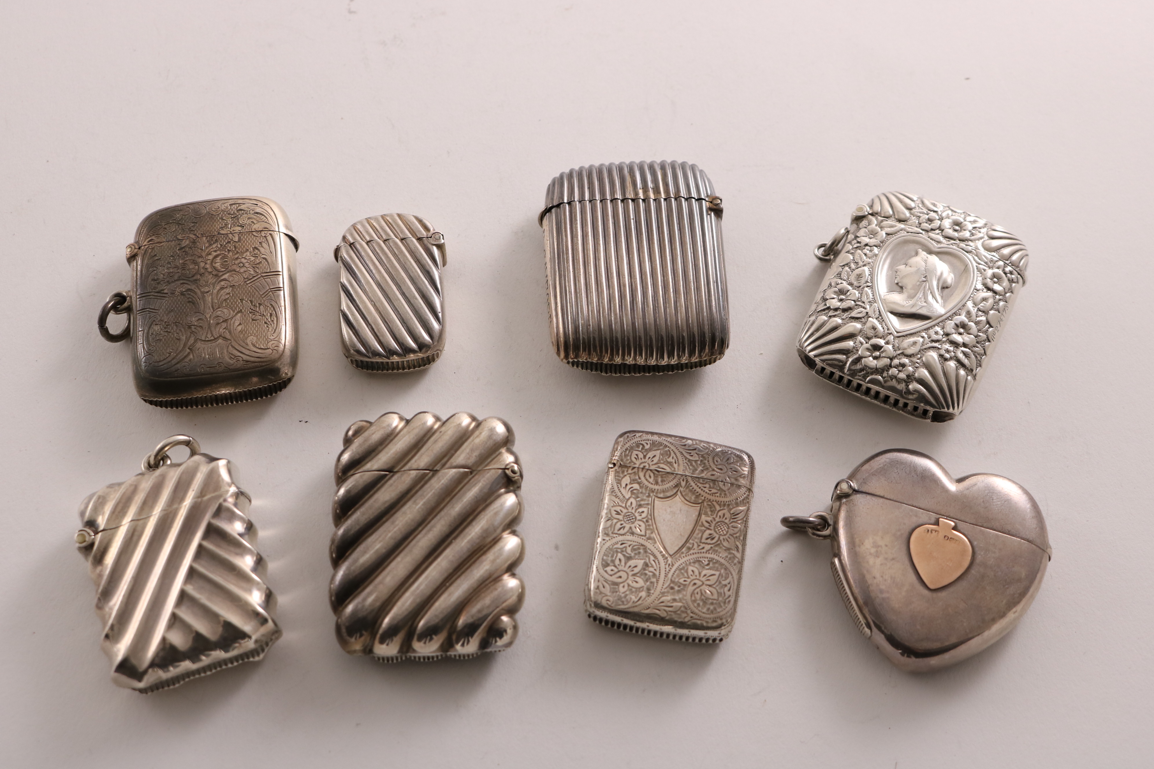 EIGHT VARIOUS LATE VICTORIAN SILVER VESTA CASES including a heart-shaped example with an applied