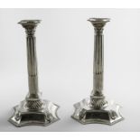 A PAIR OF GEORGE II COLUMN CANDLESTICKS on domed and shaped cruciform bases with an applied stiff