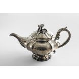 A WILLIAM IV TEA POT of shaped circular outline with fluting, a leaf-capped, c-scroll handle and a