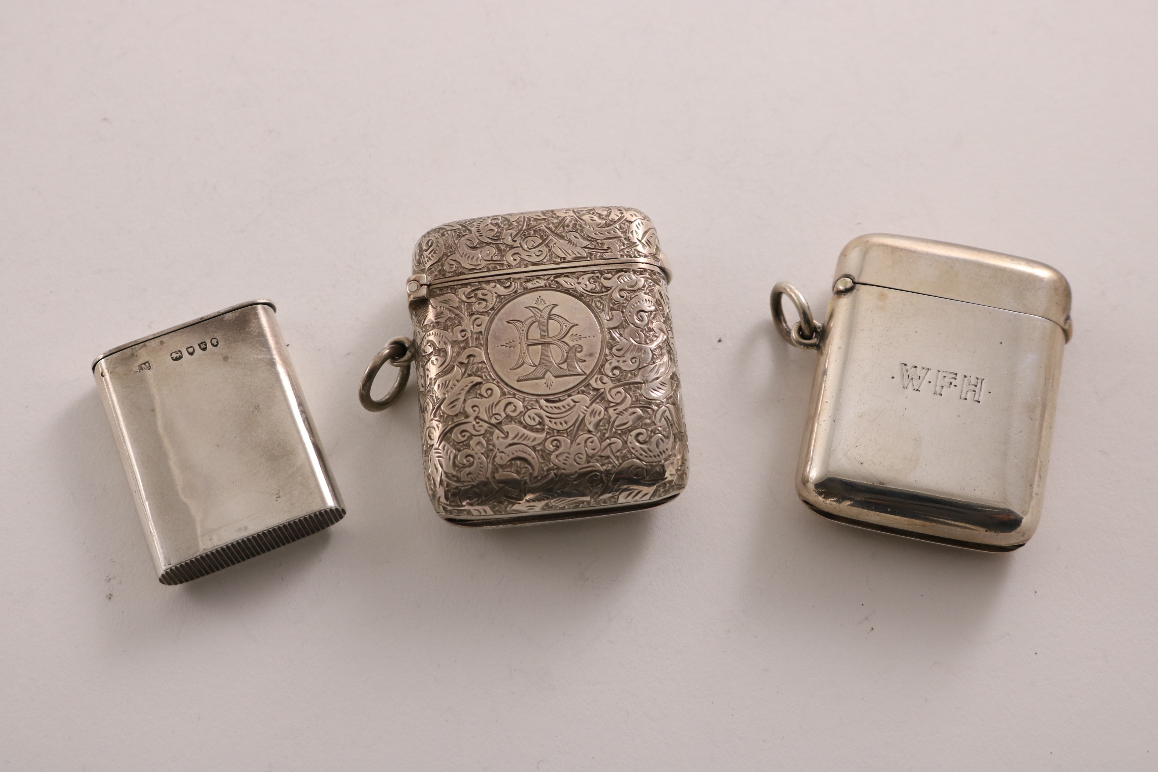 THREE LATE VICTORIAN / EDWARDIAN SILVER VESTA CASES by Sampson Mordan & Co. of London:- a plain "